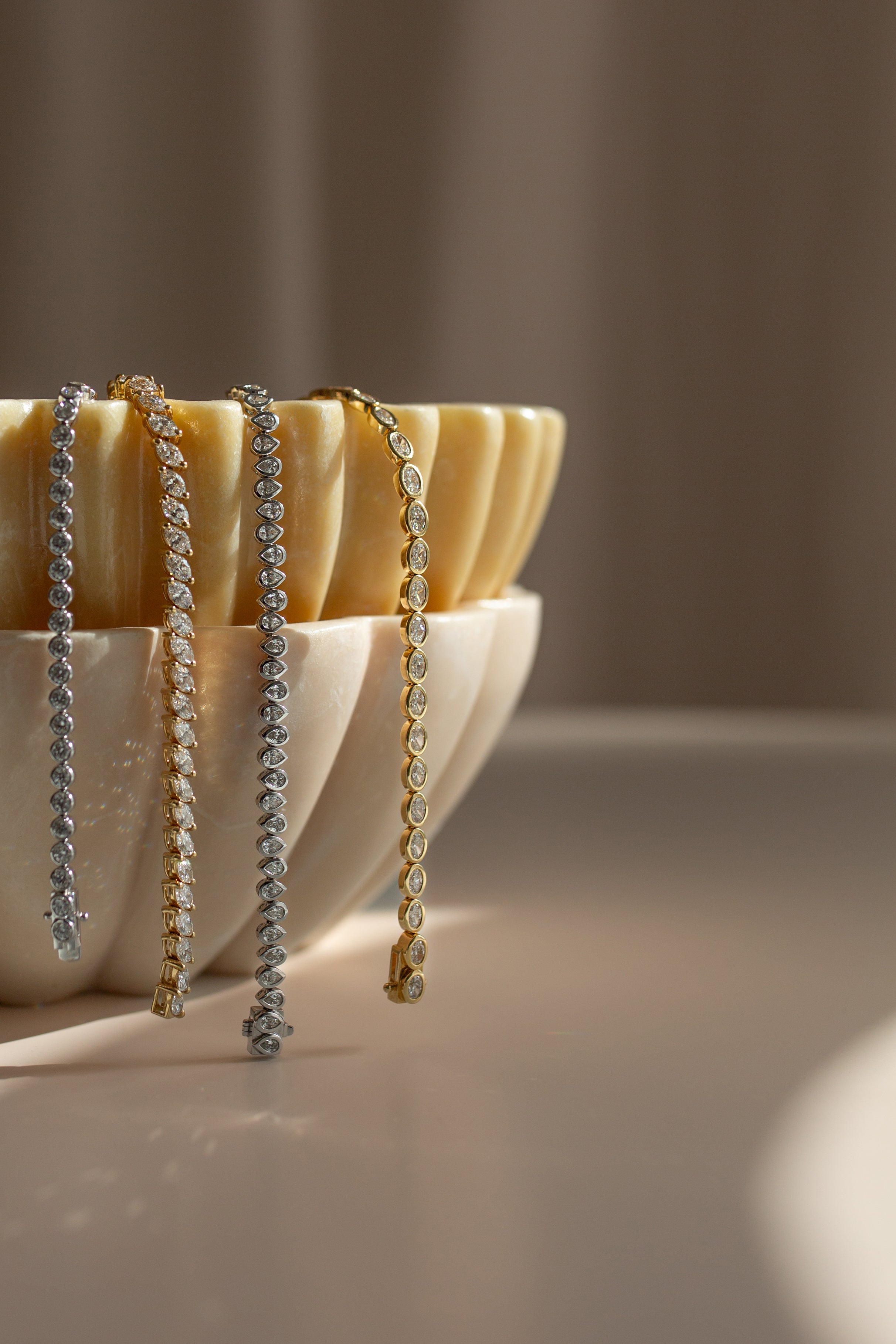 Two beaded bracelets displayed on a shell with a neutral background by Saint Stones.