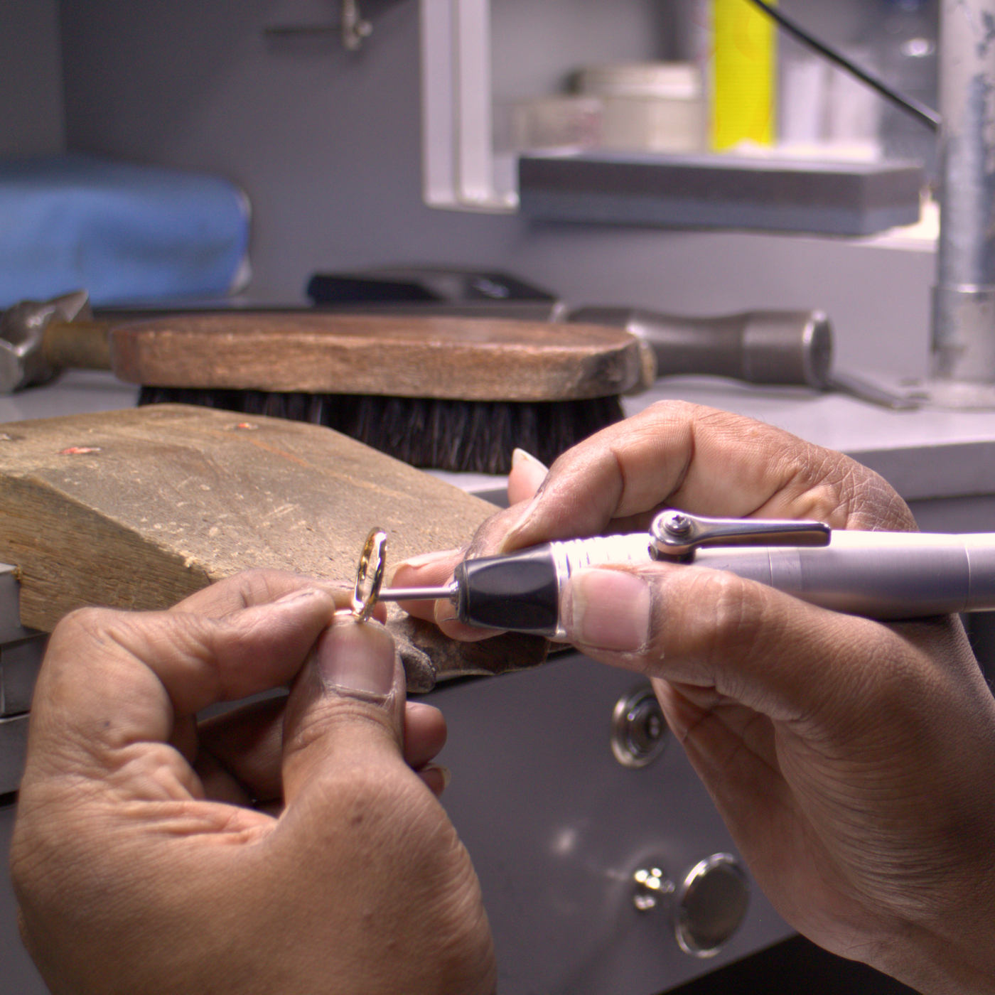 Close-up of hands crafting a custom engagement ring with tools in a jewellery workshop by Saint Stones.