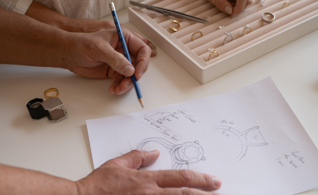 Saint Stones founders sketching a jewellery design on paper with tools during an initial client chat.