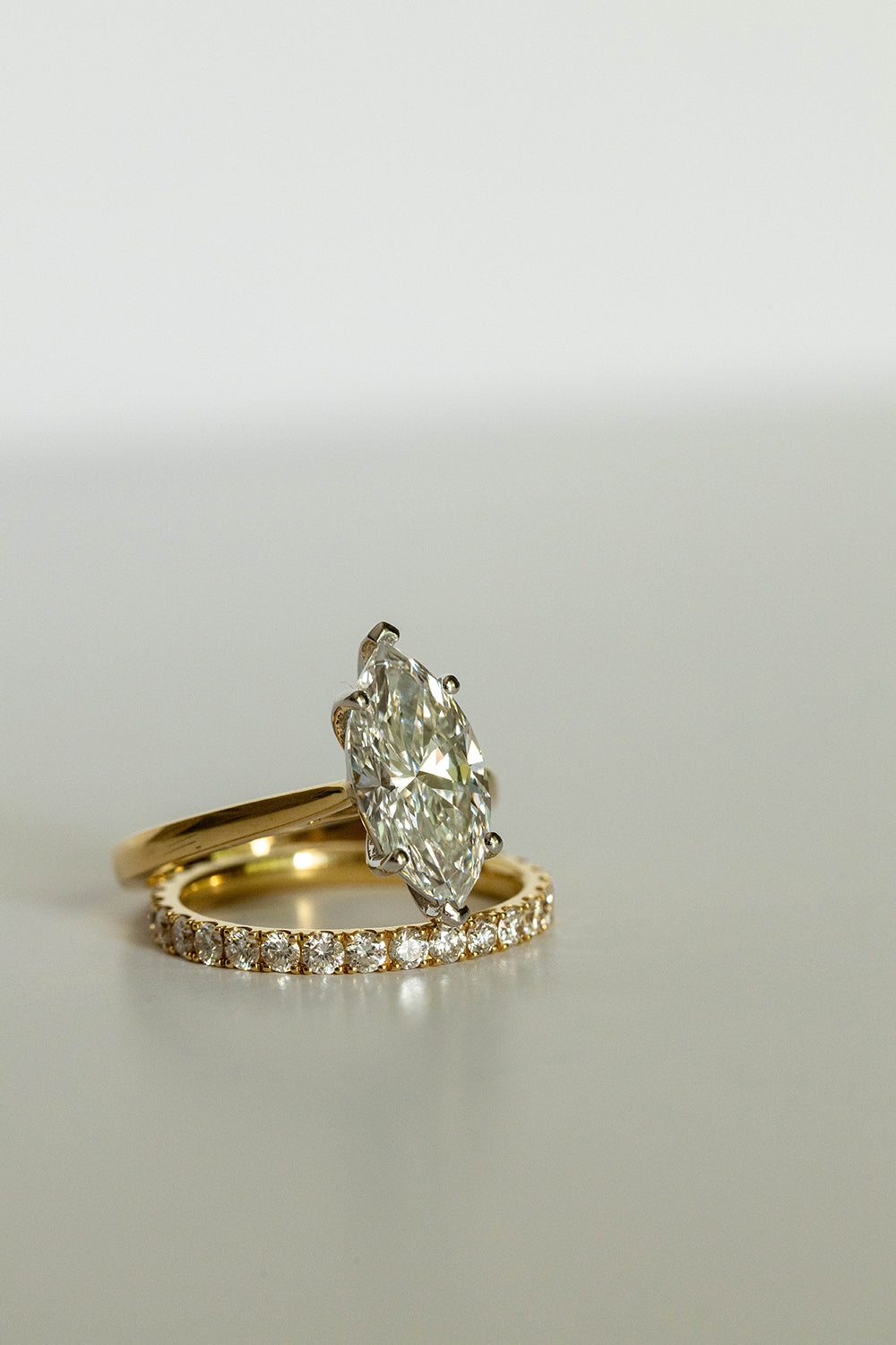 Gold ring with a large diamond and matching band by Saint Stones on a light gray background.