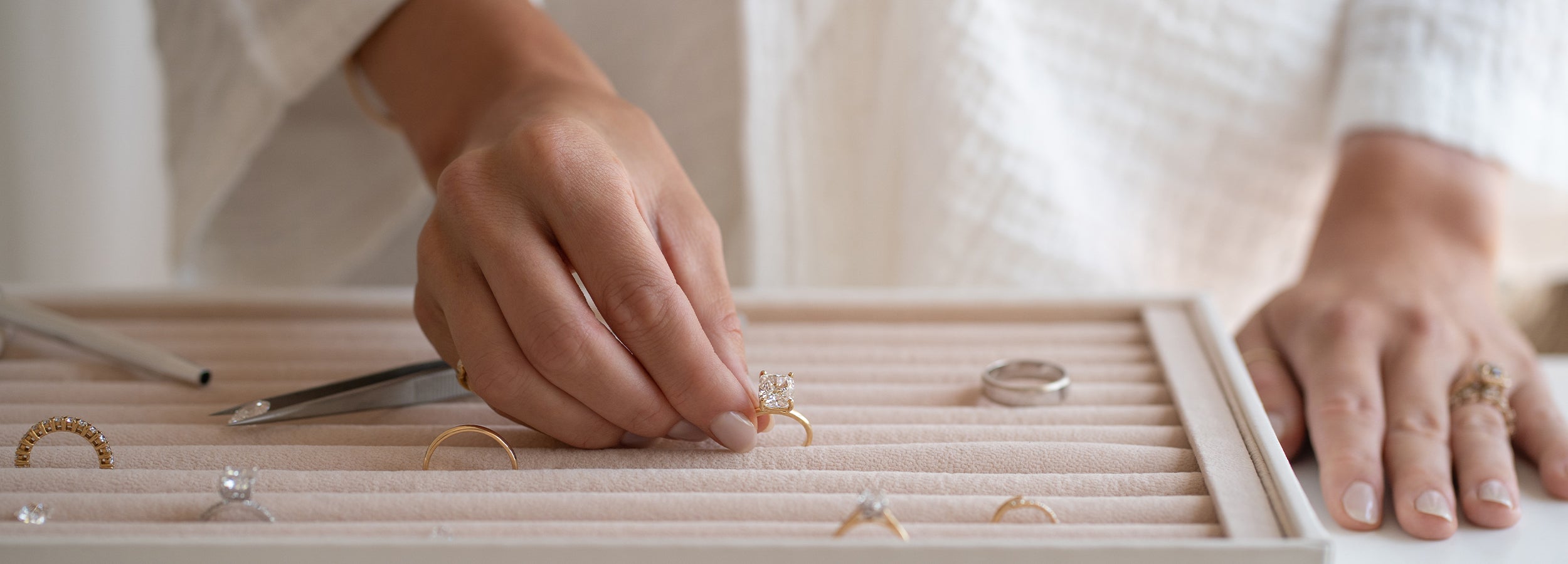 Saint Stones founders organizing jewelry on a wooden tray with a neutral background.